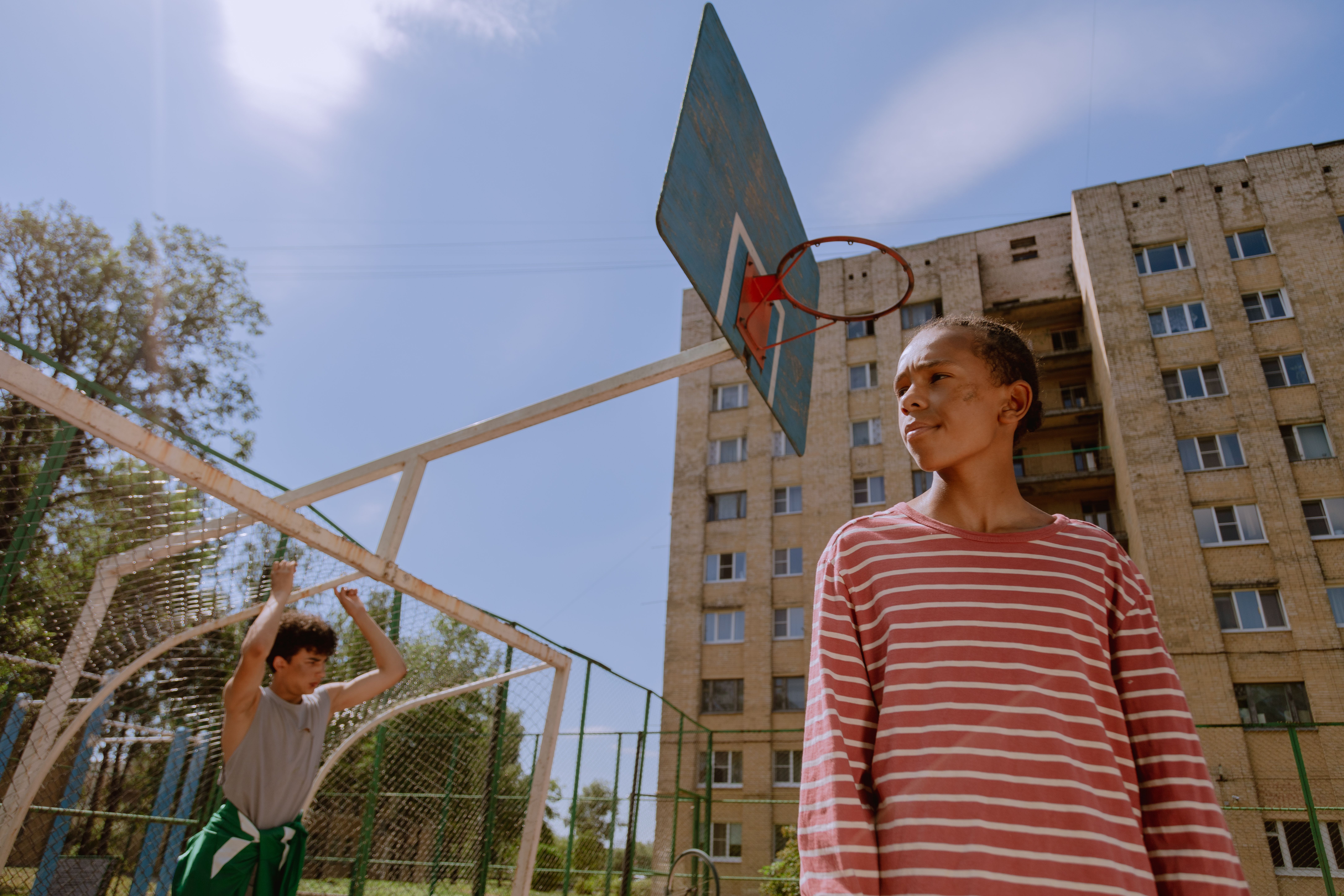 Two teenagers on an outdoor neighborhood basketball court